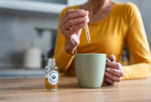 Senior woman enjoying her morning routine by adding organic cannabis oil to her tea, embracing wellness and relaxation at home